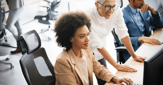 Two professionals working on a desktop in an office