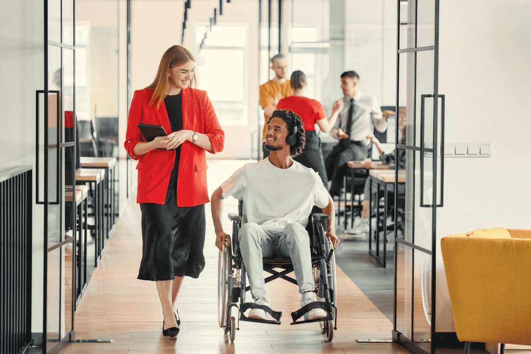 Woman walking in an office with a man in a wheelchair