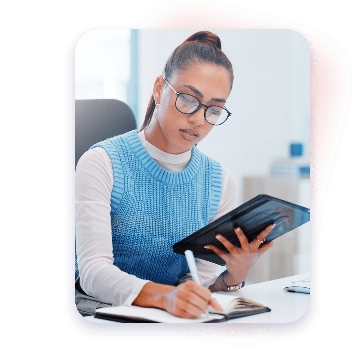woman at work writing in agenda book while holding tablet